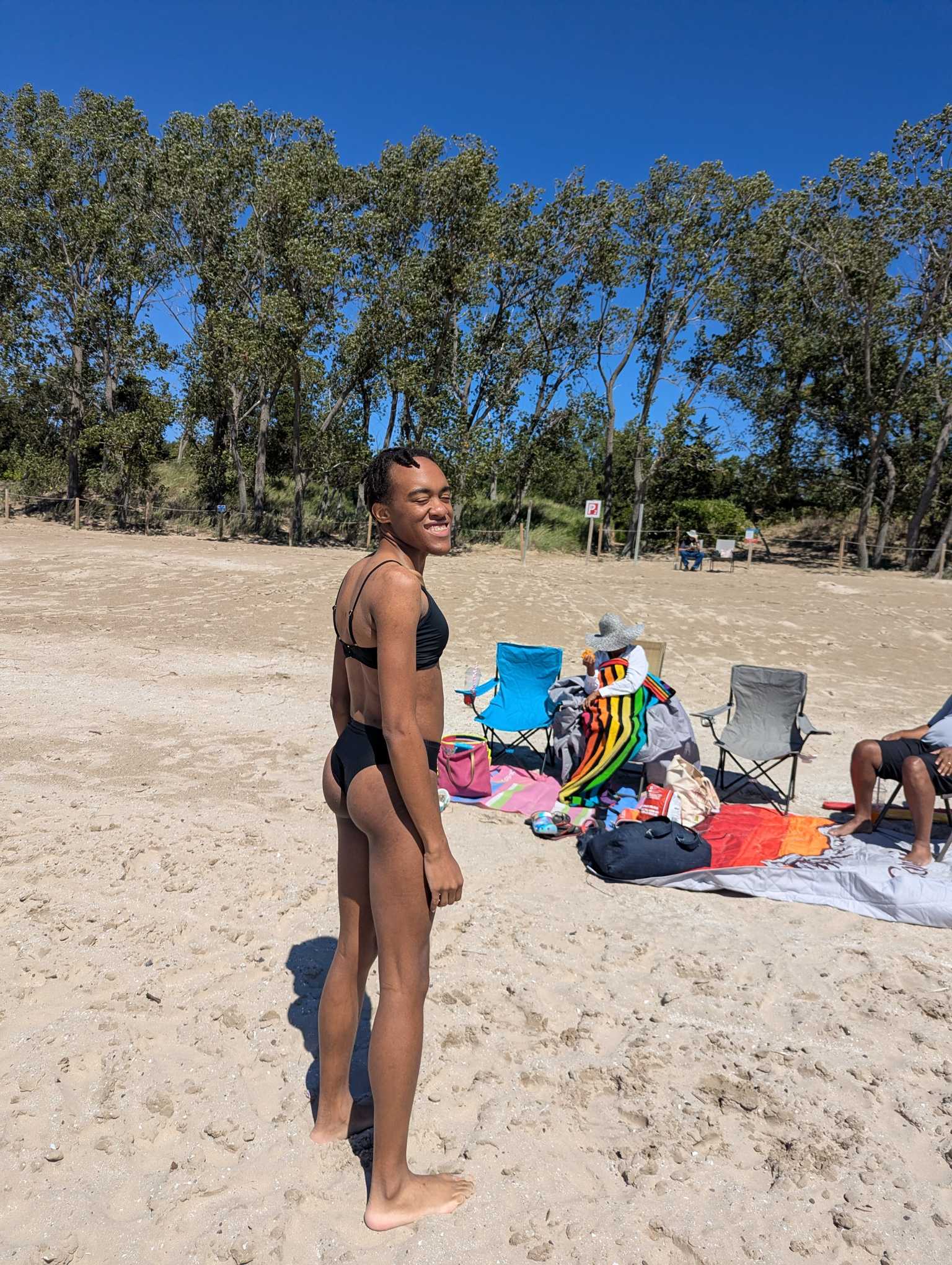 Another picture of Jessica on the beach in a bikini. She's smiling with her eyes closed, and her back facing the camera.